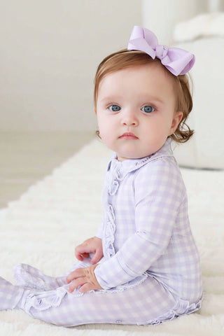 Caden Lane Peter Pan Collar Ruffle Zipper Footie - Lilac Gingham
Baby wearing a purple checkered outfit with a matching headband on a white background