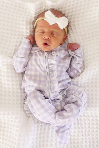 Caden Lane Peter Pan Collar Ruffle Zipper Footie - Lilac Gingham
Newborn baby wearing a gray checkered outfit and white headband on a white blanket.