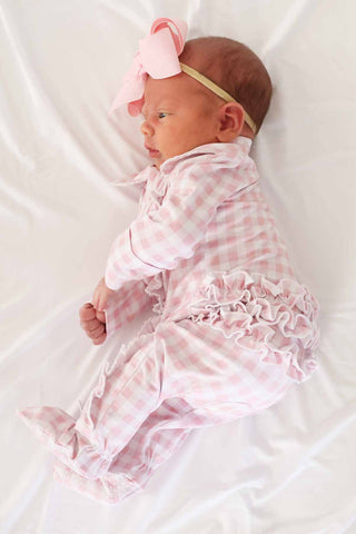 Caden Lane Peter Pan Collar Ruffle Zipper Footie - Rosy Gingham
Newborn baby in a pink checkered outfit with a matching headband on a white background