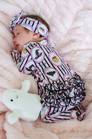 Caden Lane Ruffle Zipper Footie - Glow in the Dark Galloween
A baby sleeping on a pink plush blanket, wearing a matching Halloween-themed bodysuit and headband. The outfit features black and white stripes with pink circular borders, black bats, pumpkins, and ghosts.