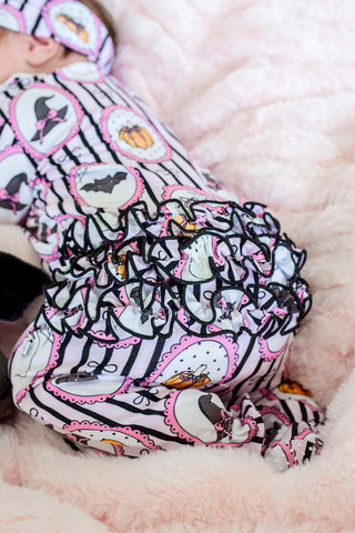 Caden Lane Ruffle Zipper Footie - Glow in the Dark Galloween
A baby wearing a Halloween-themed bodysuit and matching hat, lying on a soft pink blanket. The bodysuit has a black and white striped pattern with pink ruffles, featuring cartoon ghosts, bats, and pumpkins.
