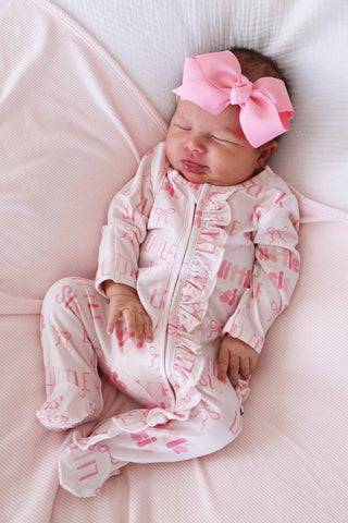 Caden Lane Ruffle Zipper Footie - Little Sis Bows
Newborn baby in pink outfit with a large bow on a white blanket