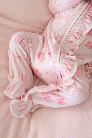 Caden Lane Ruffle Zipper Footie - Little Sis Bows
Baby outfit with pink text on a pink background