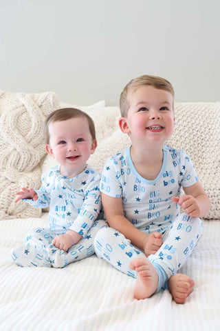Caden Lane Two Piece Pajama Set - Big Bro Stars
Two children in matching pajamas sitting on a bed.