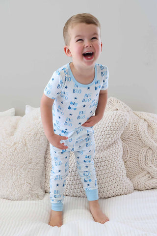 Caden Lane Two Piece Pajama Set - Big Bro Stars
Child wearing blue pajamas with car pattern on a bed