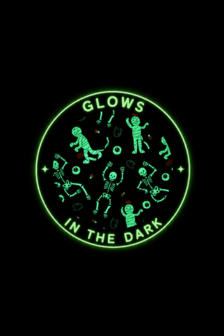 Caden Lane Two Piece Pajama Set - Glow in the Dark Eye Want Candy A circular black product featuring a glowing green graphic with cartoon astronauts and the text 'GLOWS IN THE DARK' on a solid black background.