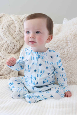 Caden Lane Zipper Footie - Little Bro Stars
Baby wearing a blue and white onesie with text and star patterns, sitting on a textured surface.