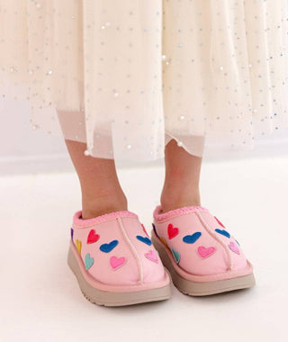 Lola and The Boys Candy Heart Sherpa Booties
Pink slippers with colorful heart patterns worn indoors.