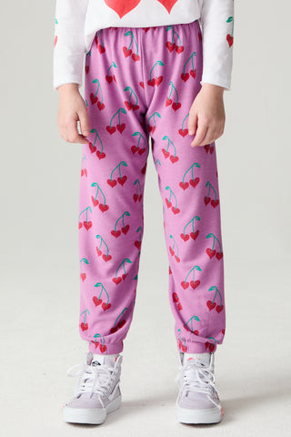 Chaser Allover Sweethearts Girls Jogger
A child wearing pink jogger-style pants with an allover red cherry print, paired with a white long-sleeve top and white sneakers, shown from the waist down against a light gray studio background.