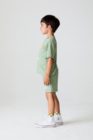 Chaser On The Green Tee
Child wearing a green t-shirt and shorts set with white sneakers on a white background
