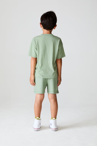 Chaser On The Green Tee
Child wearing a green outfit standing against a white background