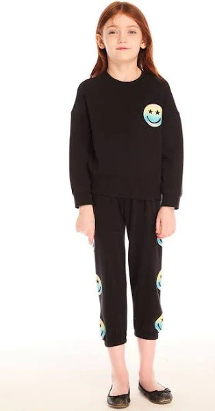 Chaser Pastel Rainbow Smiley Pullover
Child wearing a black outfit with smiley face designs on a white background