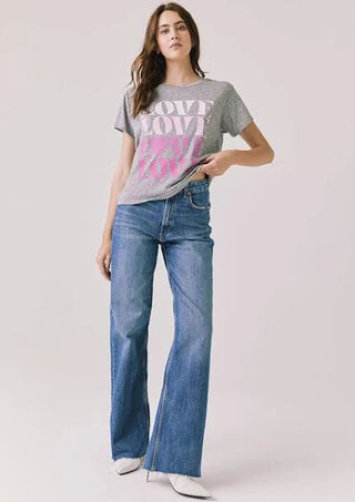 Chaser Women's Love Tee
Woman wearing a gray t-shirt with colorful text and blue jeans on a white background