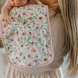 Copper Pearl Natalie Burp Cloth Set
Floral-patterned baby blanket held by a person with a doll