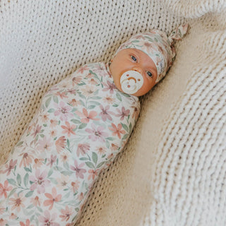 Copper Pearl Natalie Swaddle Blanket
Newborn baby wrapped in a floral blanket with a pacifier, lying on a textured beige surface.