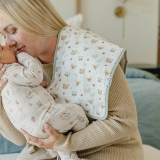 Copper Pearl Wilder Burp Cloth Set
Woman holding a baby wrapped in a patterned blanket indoors.