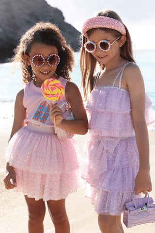 Lola and The Boys Crystal Chill Out Tank Top
Two young girls in matching dresses standing on a beach.