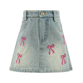 Lola & The Boys Cutie Bows denim skirt featuring bow accents, high waist, and classic blue denim fabric on a model.