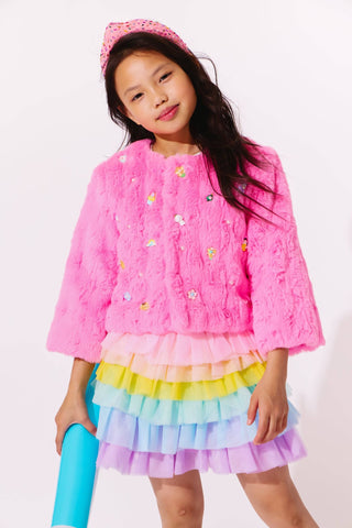 Lola and The Boys Cutie Charms Faux Fur Jacket
Young girl wearing a pink top with floral embellishments and a colorful rainbow skirt on a white background