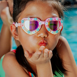 Bling2o Daisies At Dawn Heart Swim Goggles
Child wearing colorful sunglasses blowing a kiss by a pool