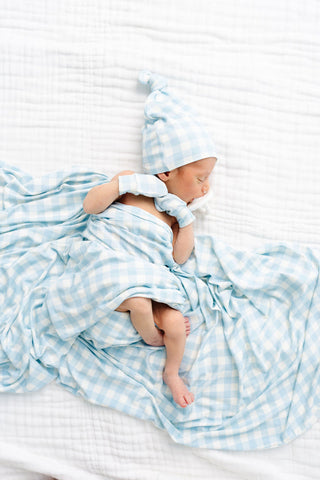 Lou Lou and Company Knit Swaddle Blanket - Walker
Newborn baby wrapped in a blue checkered blanket and hat on a white striped background