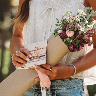 K'lani "Bloom" Maroon & Pink with Pressed Flowers Hair Tie Bracelets
Person holding a bouquet of flowers and a box of jewelry