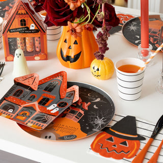 Daydream Society Trick or Treat Pumpkin Body Shimmer
A styled Halloween tabletop scene with party tableware, including orange and black haunted-house plates, matching napkins, a ghost-shaped condiment container, a small jack-o'-lantern candle holder, and floral centerpieces on a white table.