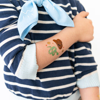 Jollity & Co Yeehaw Temporary Tattoos
Person wearing a temporary tattoo of a turtle and cowboy hat on their arm, with a blue and white striped shirt.
