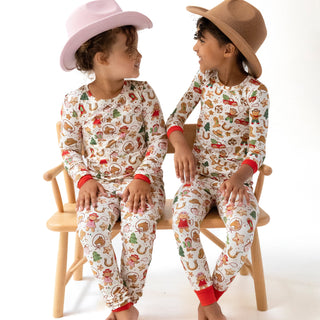 Angel Dear Long Sleeve Loungewear Set - Cowgirl Christmas
Two children wearing matching pajamas with a gingerbread theme, sitting on a chair.