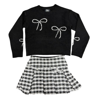 Black and white houndstooth skort from Flowers By Zoe, styled with black bows and a black sweater in the image.