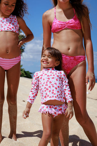 Feather 4 Arrow Sandy Toes Rashguard Swim Set - Multi
Three children in pink and white swimsuits on a beach