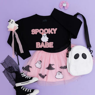 Sweet Wink Spooky Babe Sequin Halloween Tutu
Black sweatshirt with 'Spooky Babe' text, pink skirt with ghost patterns, black high-top sneakers, and white ghost bag on a purple background.