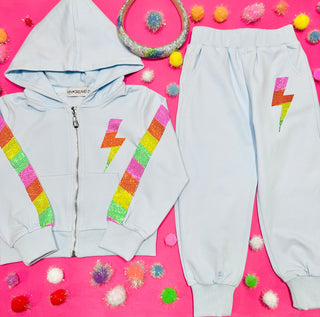 Mini Dreamers Miley Crystal Bolt Zip Up Hoodie and Sweatpant Set
Children's hoodie and pants with colorful lightning bolt designs on a pink background with decorative items.