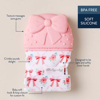 Itzy Ritzy Teething Mitt - Bow Pink silicone baby teether with floral design and bow details on a beige background
