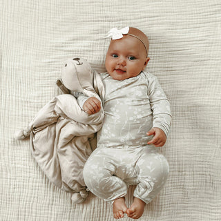 Gunamuna Bunny Lovey - Lucy
Baby lying on a textured surface holding a soft toy, wearing a white outfit with a bow.