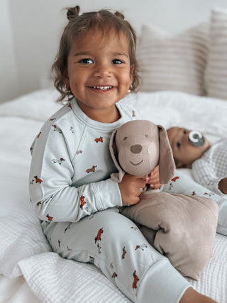Gunamuna Pup Lovey - Mutts
Child in pajamas holding a plush dog toy on a bed