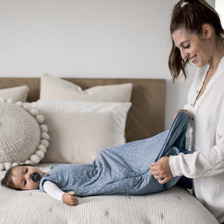 Gunamuna Sleep Sack 1.0 TOG - Dream
Woman helping a baby put on blue pajamas with white polka dots on a bed.