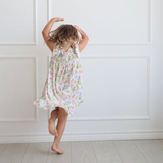 Hollis Baker Gown - Tulips
Child in a floral dress standing against a white paneled wall.
