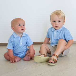 Hollis Baker Trey Polo - Blue Stripe
Hollis Baker Tripp Romper - Blue Stripe
Two young children wearing matching blue polo shirts sitting on a light wood floor.