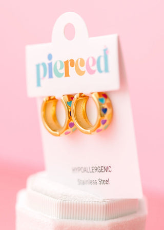 Pierced Co. Huggies - Chunky Rainbow Heart
Pair of gold hoop earrings with colorful heart details on a 'pierced' branded card against a pink background.