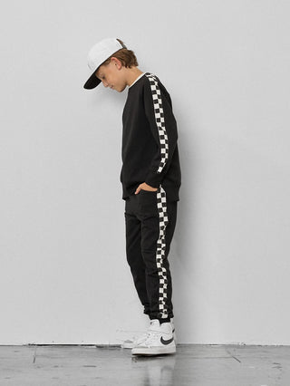 Little Bipsy Stripe Checkered Pullover - Black
Person wearing a black and white checkered outfit with a cap against a plain background