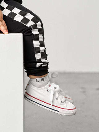 Little Bipsy Stripe Checkered Jogger - Black
Person wearing black and white checkered pants with a white sneaker on a gray background