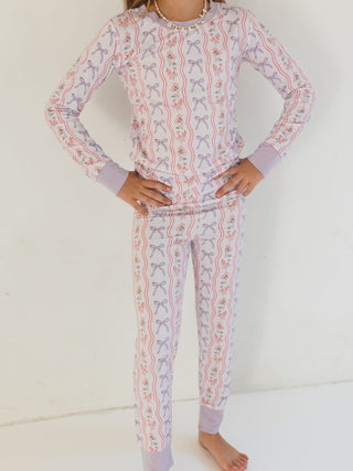 In My Jammers Two Piece Set - Purple Amelia Bow
Child wearing a pajama set with bow pattern on a white background