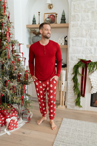 In My Jammers Solid Red Santa Men's Top
In My Jammers Santa Men's Jogger
Man wearing red pajamas with white patterns in a festive living room.
