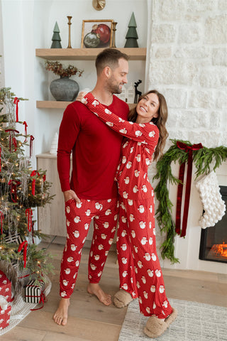 In My Jammers Santa Women’s SetCouple wearing matching red pajamas with white patterns in a festive living room.