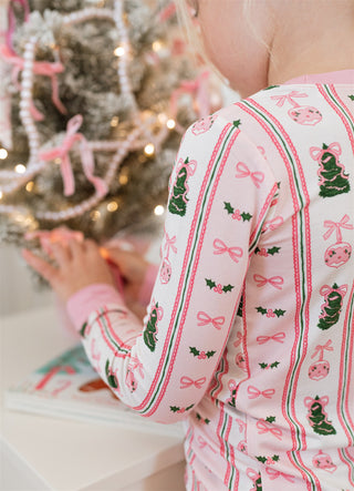 In My Jammers Pinkmas Two Piece Set 
Child in festive pajamas near a decorated Christmas tree