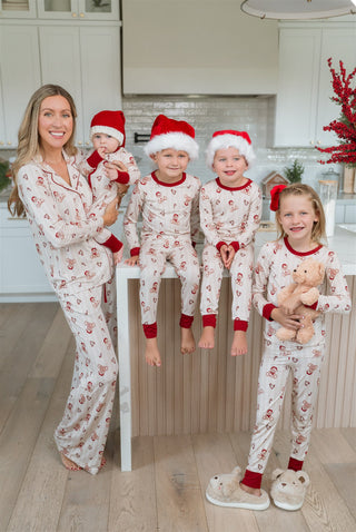 In My Jammers Bear-y Merry Two Piece Set
Family in matching pajamas with Santa hats in a kitchen setting.