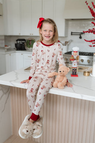In My Jammers Bear-y Merry Two Piece Set
Young girl in pajamas sitting on a kitchen counter with a teddy bear