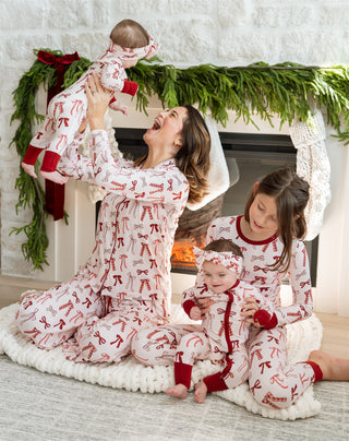 In My Jammers Merry Little Bows Zipper Romper
Family in matching pajamas in front of a fireplace with Christmas decorations.
