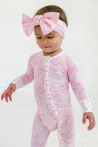 In My Jammers Headband - Cora Floral Bows
Child wearing a pink floral onesie and headband on a white background